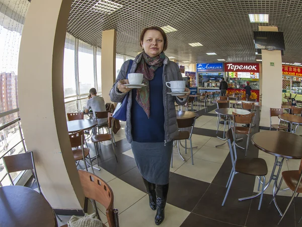 Pushkino, Russia, on March 17, 2015. The woman bears two cups of coffee in cafe in shopping center, fisheye view.
