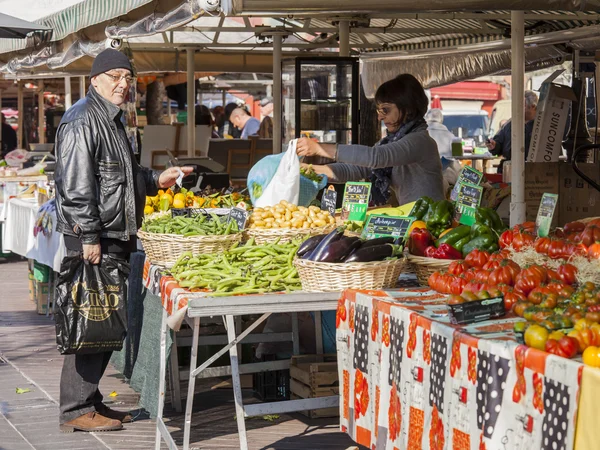 Nice, France, on March 11, 2015. Buyers in the market choose vegetables and fruit