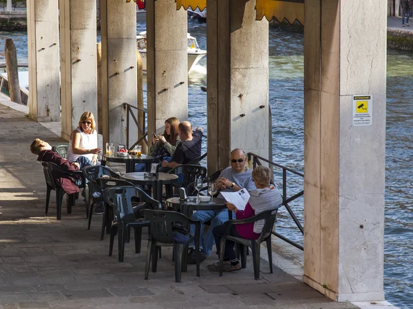 VENICE, ITALY - on APRIL 29, 2015. People have a rest and eat in summer cafe on the bank of the Grand channel (Canal Grande).