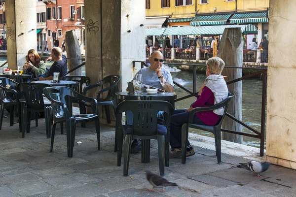 VENICE, ITALY - on APRIL 29, 2015. People have a rest and eat in summer cafe on the bank of the Grand channel (Canal Grande).