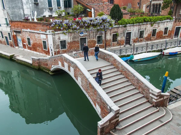 VENICE, ITALY - on MAY 3, 2015. The bridge with steps through the street canal, the top view from a house window on the bank of the channel