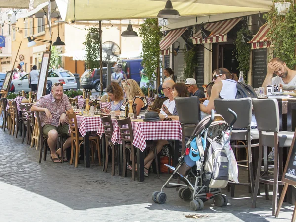 ROME, ITALY, on AUGUST 25, 2015. Picturesque summer cafe on the city street. People have a rest and eat at tables