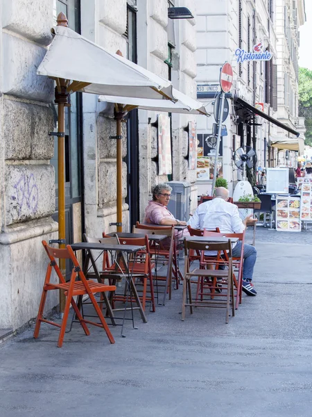 ROME, ITALY, on AUGUST 25, 2015. Picturesque summer cafe on the city street. People have a rest and eat at tables