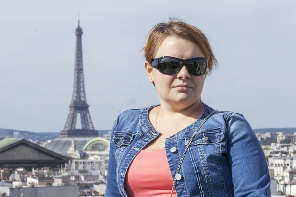 PARIS, FRANCE, on SEPTEMBER 1, 2015. The happy tourist is photographed on a survey platform against the Eiffel Tower. The Eiffel Tower is one of the most visited and recognizable sights of the world