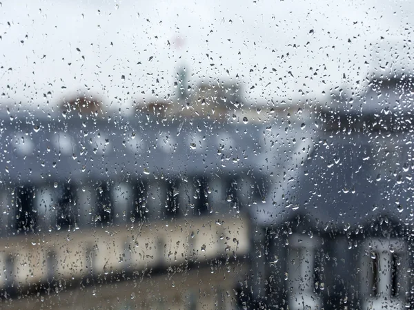 PARIS, FRANCE, on AUGUST 27, 2015. A view from the window on the city in rainy weather. Roofs of Paris wet from a rain, a rain drop on glass