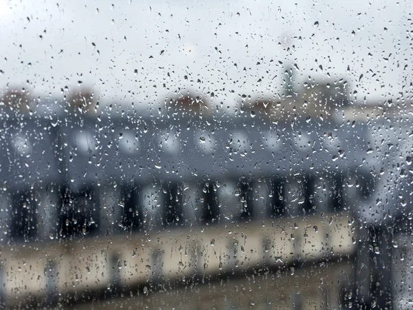 PARIS, FRANCE, on AUGUST 27, 2015. A view from the window on the city in rainy weather. Roofs of Paris wet from a rain, a rain drop on glass