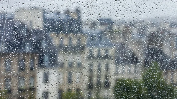 PARIS, FRANCE, on AUGUST 27, 2015. A fragment of an architectural complex of the square in front of the Centre Georges Pompidou, a look through a wet window. It is raining, water drops on glass, focus on drops