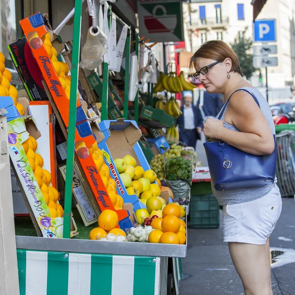 PARIS, FRANCE, 30AVGUSTA 2015. Urban view. Typical Parisian street in the bright sunny day. The woman buys fruit in the street mini-market