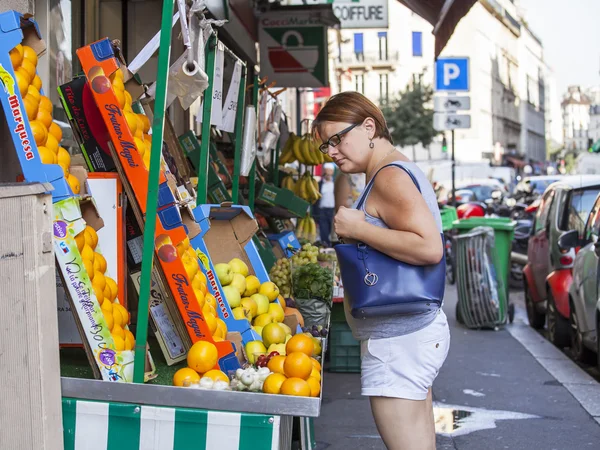 PARIS, FRANCE, 30AVGUSTA 2015. Urban view. Typical Parisian street in the bright sunny day. The woman buys fruit in the street mini-market