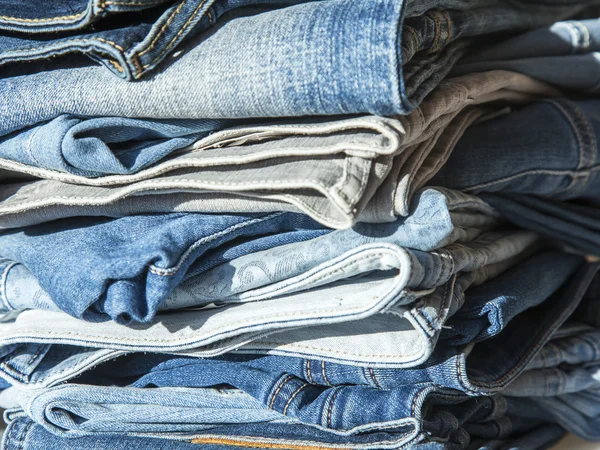 Pile of jeans of various shades on a show-window of shop