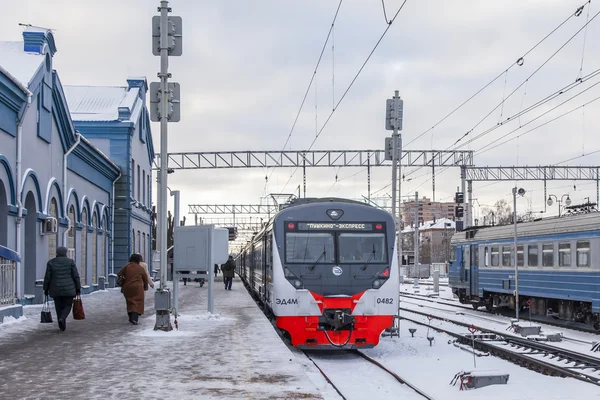 PUSHKINO, RUSSIA, on DECEMBER 17, 2015. Winter day. The suburban electric train stopped at a platform of the railway station. Passengers go on a platform