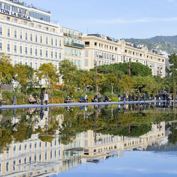 NICE, FRANCE, on JANUARY 7, 2016. The flat fountain in Promenade du Paillon park. An architectural complex of buildings in the boulevard and its reflection in water. People walk on a promenade