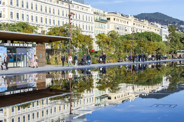 NICE, FRANCE, on JANUARY 7, 2016. The flat fountain in Promenade du Paillon park. An architectural complex of buildings in the boulevard and its reflection in water. People walk on a promenade