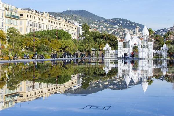 NICE, FRANCE, on JANUARY 7, 2016. The flat fountain in Promenade du Paillon park. An architectural complex of buildings in the boulevard and its reflection in water. People walk on a promenade