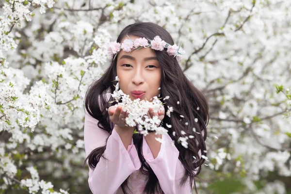 Girl in Pink Ao Dai blowing petals