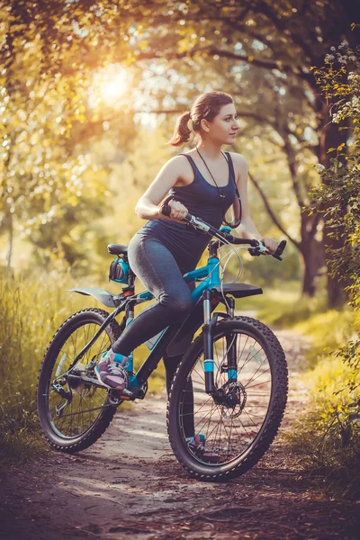 Woman cyclist rides in the forest on a mountain bike.