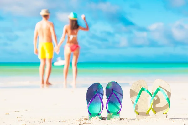 Picture of two flip flops with young couple on beach backgroung