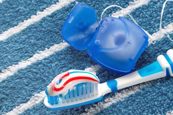 Dental floss and a blue toothbrush on a towel
