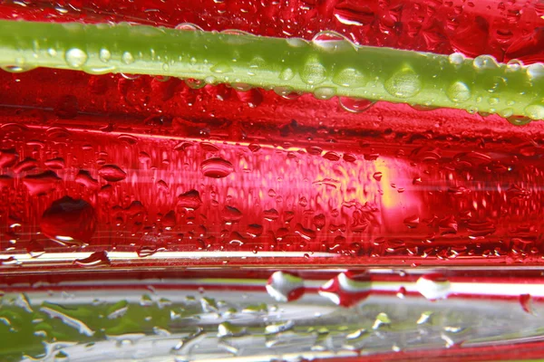 Shiny water drops sprayed on textured red surface.