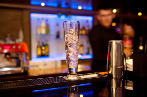 Tall glass with ice cubes on the bar counter