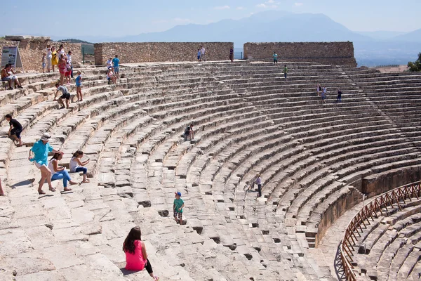 PAMUKKALE, TURKEY - September 13, 2015: Tourists regard antique amphitheater in the ancient city of Hierapolis. Pamukkale, Turkey.  Pamukkale is included in the UNESCO World Heritage List
