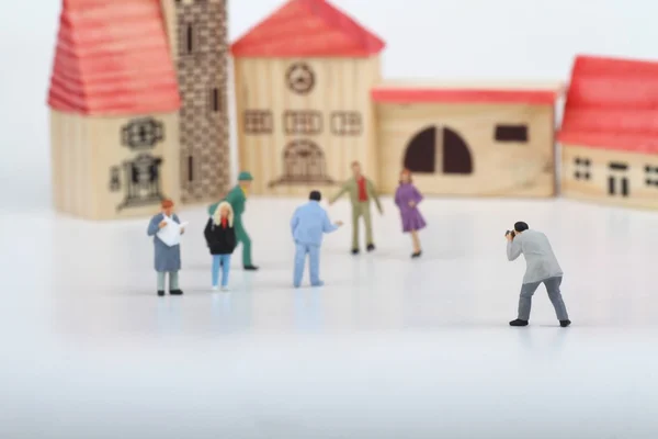 Miniature of a street photographer taking pictures of strangers walking on ta white background