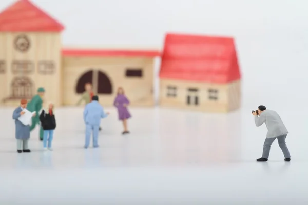 Miniature of a street photographer taking pictures of strangers walking on ta white background