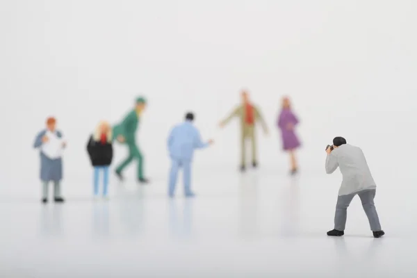 Miniature of a street photographer taking pictures of strangers walking on ta white background