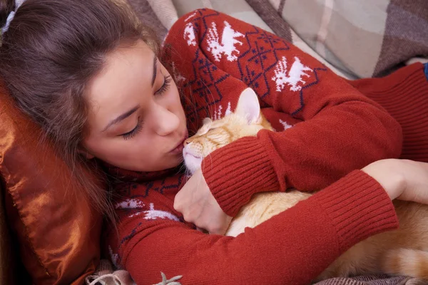Cute girl kisses a red cat