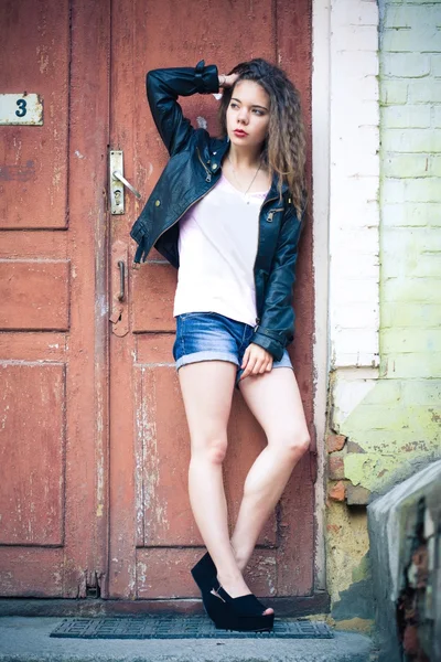 Young woman in jeans shorts and leather jacket
