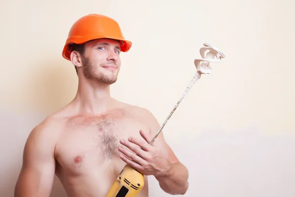 Man in helmet with a mixer for plastering