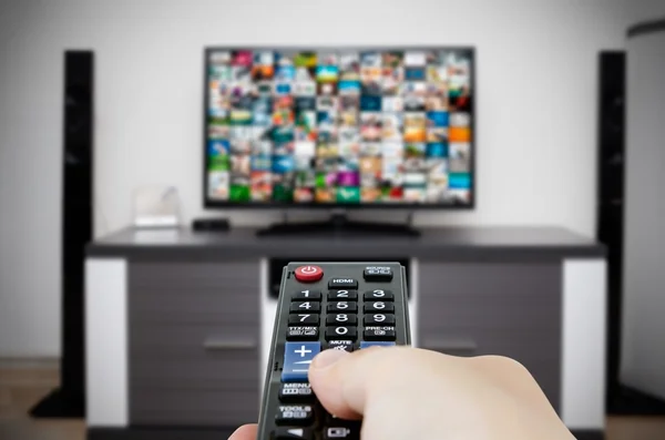 Watching television in modern TV room. Hand holding remote