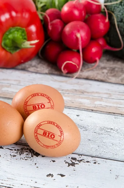 Healthy eggs with BIO stamp. Vegetables in background.