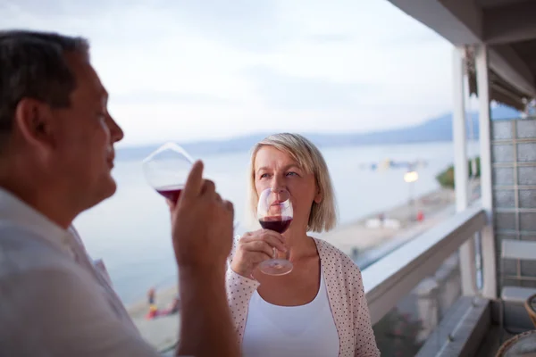 Couple Drinking Red Wine on Balcony of Beach Hotel