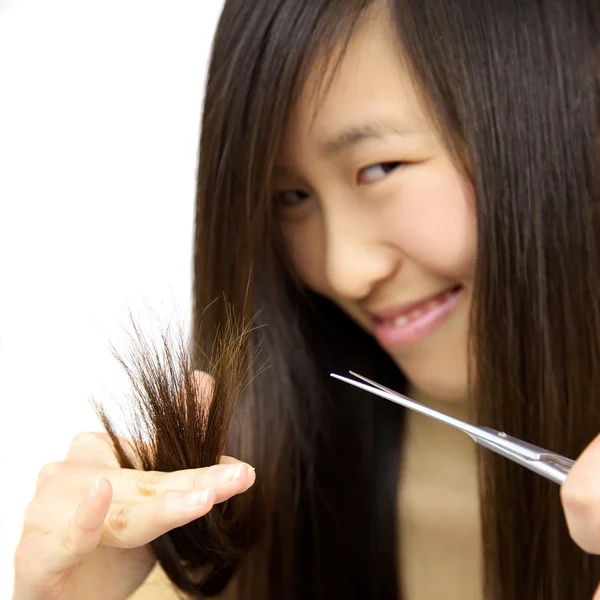 Happy asian girl cutting split dead ends hair