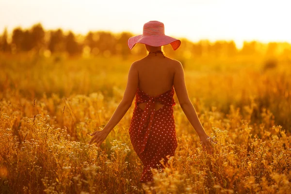 Woman in a hat walking through fields of flowers