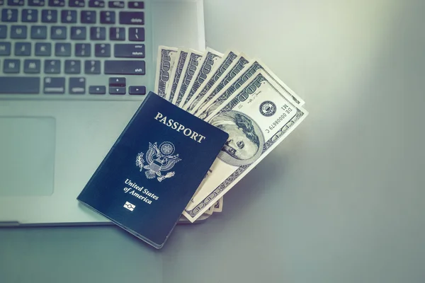 Booking travel option abroad online concept image. Passport with American dollars onto of laptop computer.