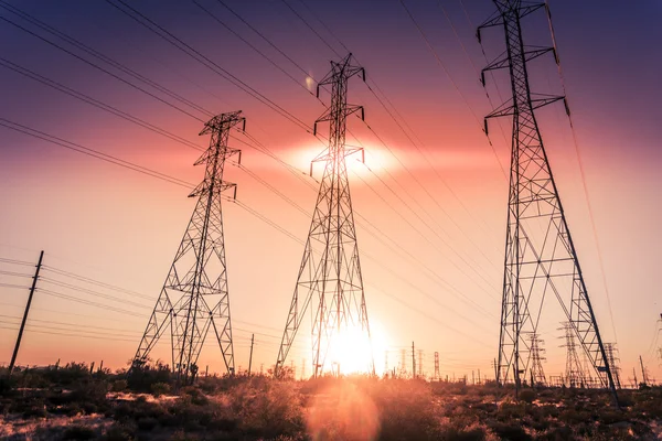 Electricity tower pylons sun going set