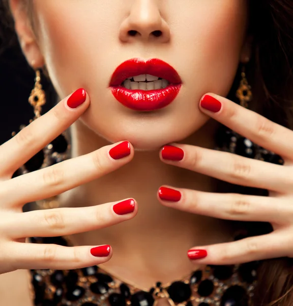 Red Sexy Lips and Nails closeup. Manicure and Makeup. Make up concept. Half of Beauty model girls face isolated on black background