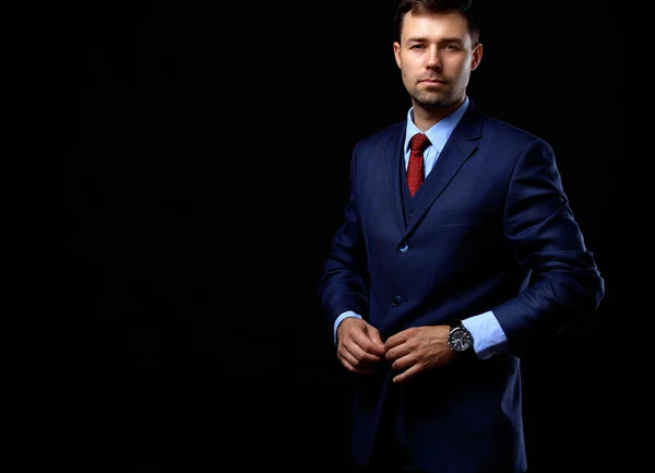 Handsome young business man standing on black background