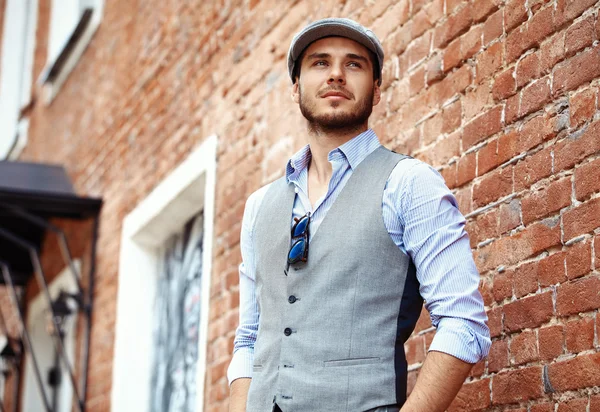 Casual young man stands with his back against brick wall