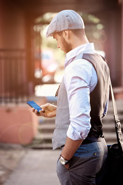 Young urban businessman professional on smartphone walking in street using app texting sms message on smartphone