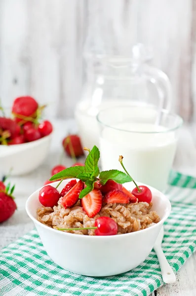 Oatmeal porridge with berries and glass of milk