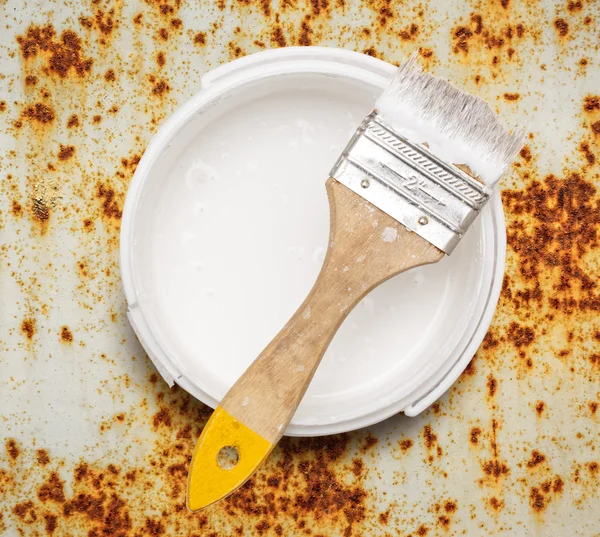 Can of white paint with brush