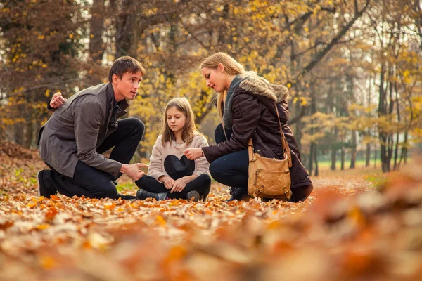 Family kneels on park ground