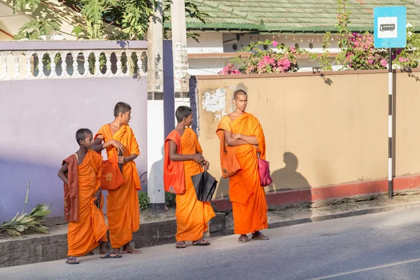 Group of buddhist monks in traditional orange robes waiting bus at station