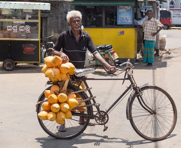 Elderly local man selling king coconuts on his bike