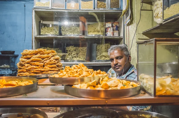 Vendor sits in store with various food