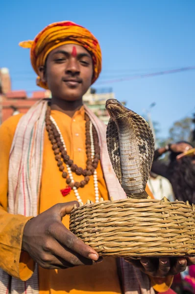Indian boy holds cobra in basket