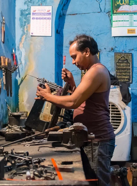 Indian man repairs sewing machine